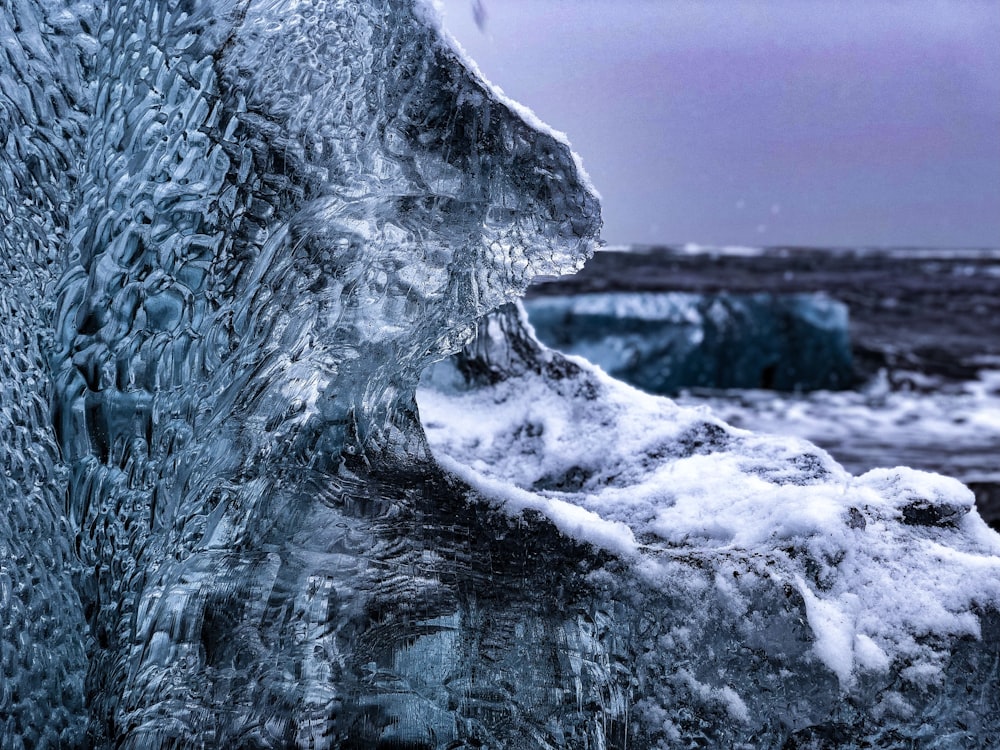 a close up of ice on a rock near a body of water