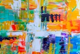 A vibrant abstract painting with bold strokes of bright colors such as teal, orange, purple, and yellow combined with white. Thick layers of paint create texture and depth, while areas of black add contrast and intrigue.