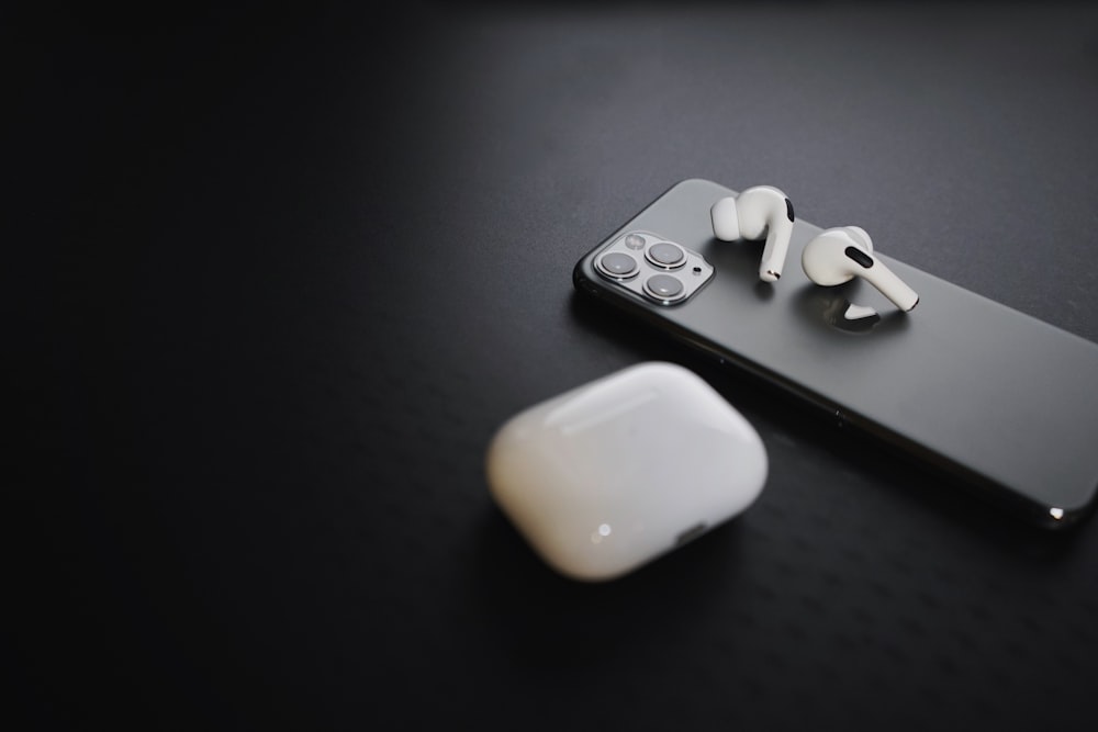 a pair of ear buds sitting on top of an iphone