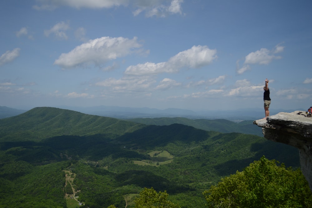 view photography of man standing on cliff during daytime