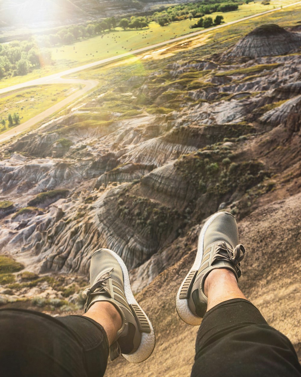 person sitting and facing the mountains and field