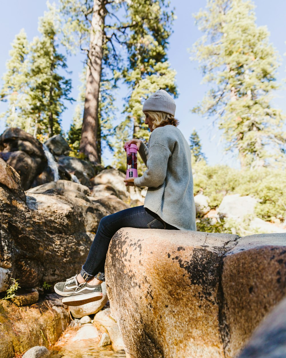 woman sitting on rock while holding blender tumbler
