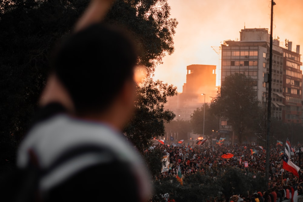 a crowd of people standing on a street next to tall buildings