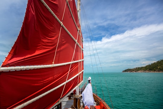 red sailboat on sea near island during daytime in Koh Samui Thailand