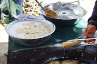 A smiling artisan carefully frying banana chips in a large traditional pan.