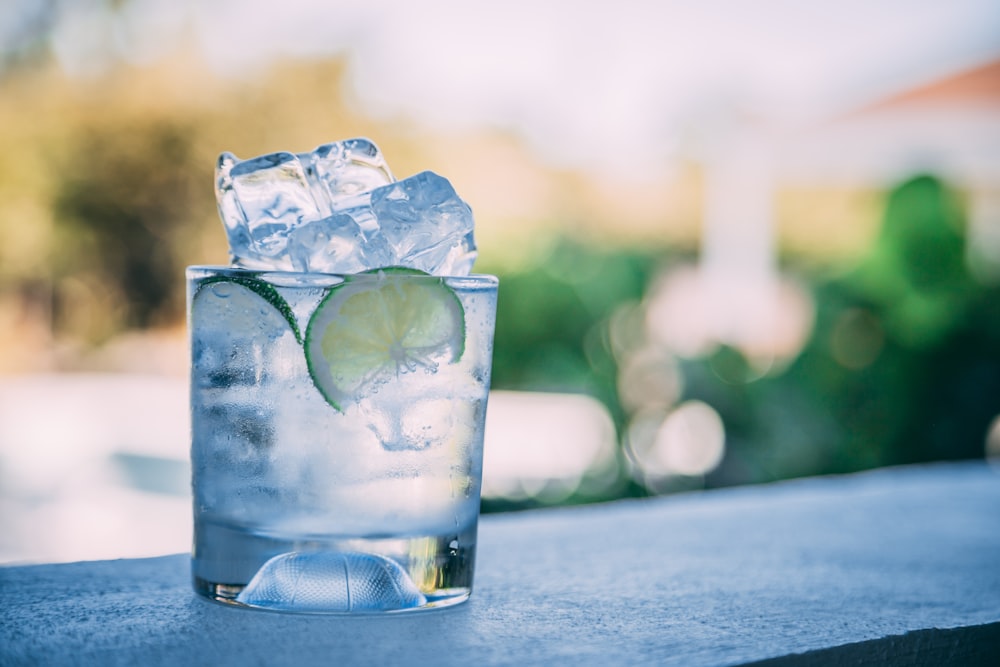 Flüssigkeit, Eis und Zitronenscheibe im klaren Trinkglas
