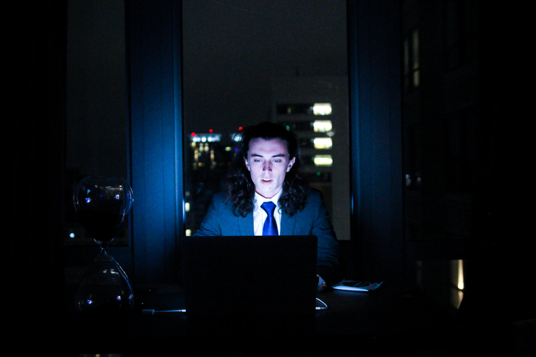 A person working at a computer in a dark, focused workspace
