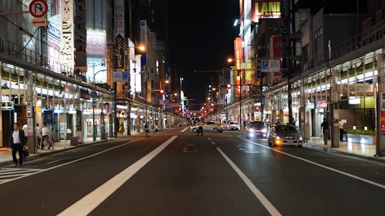 vehicles on street between lighted establishments at night in Osaka Japan