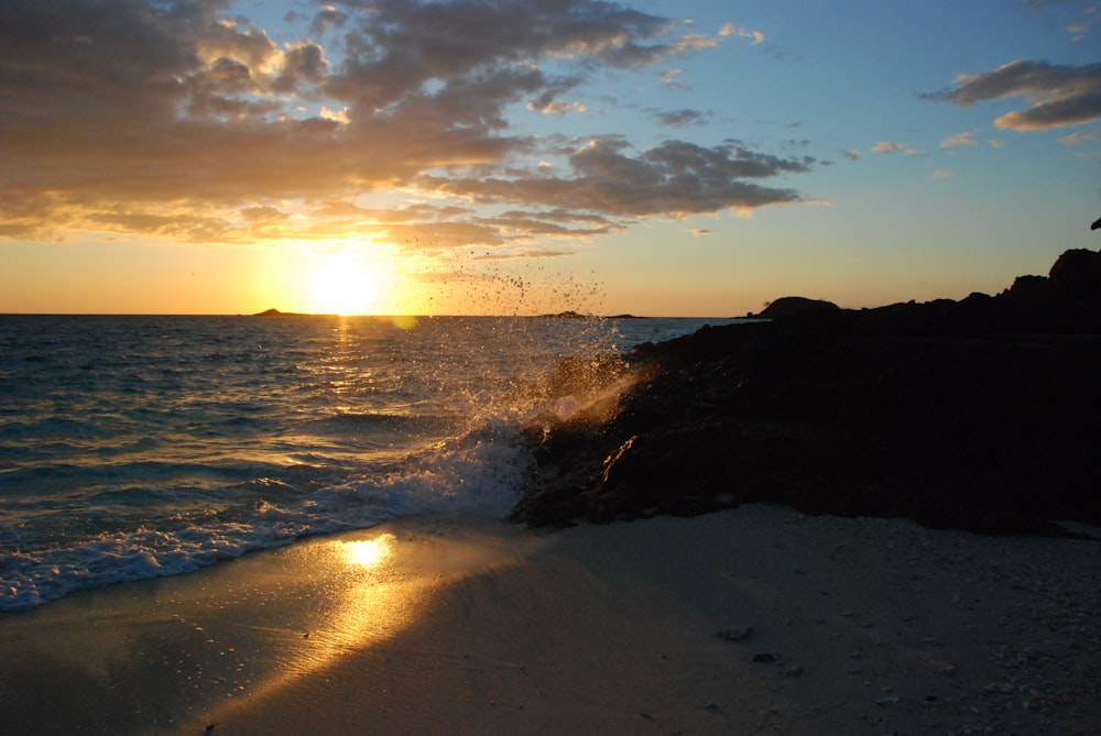 beach cliff viewing body of water during sunrise