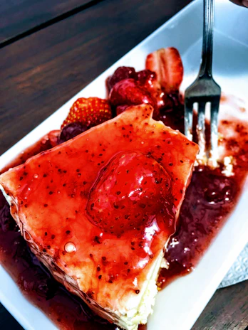 A creamy cheesecake topped with a glossy strawberry glaze and fresh whole strawberries.