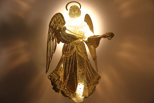 An elegant depiction of two figures standing beneath an angel, bathed in soft golden light.