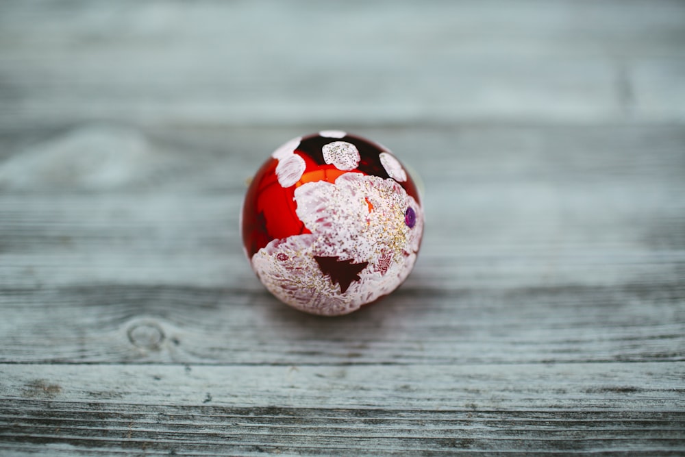 Adorno redondo de bola roja, negra y blanca sobre superficie gris