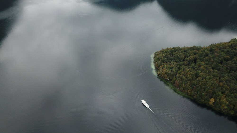 white boat on body of water beside mountain