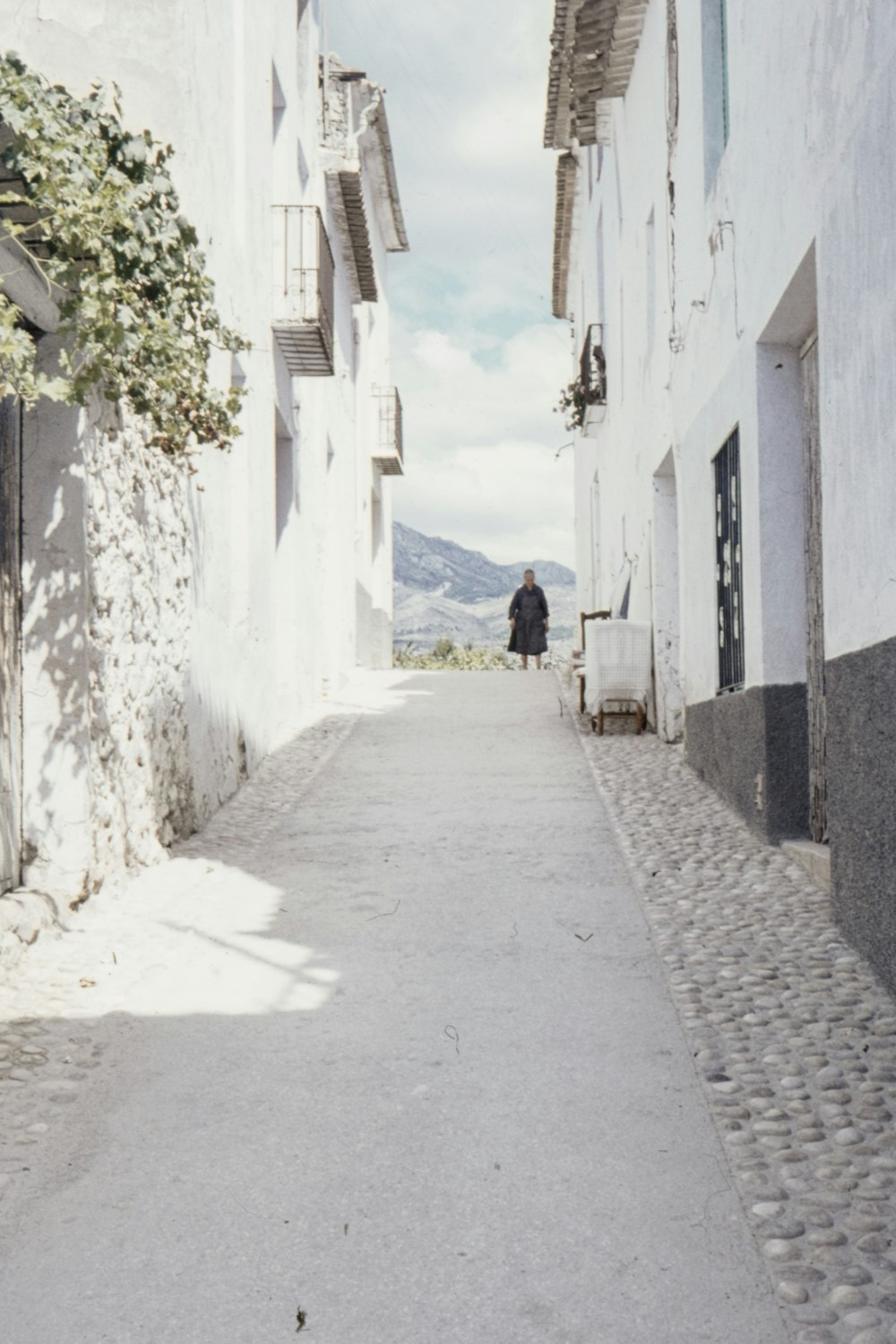 a man walking down a street next to tall buildings