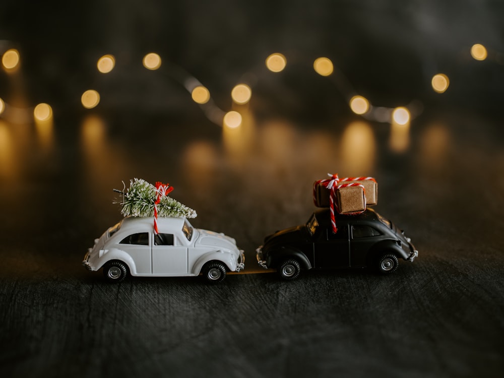 two black and white Volkswagen Beetle miniatures with cargos on top