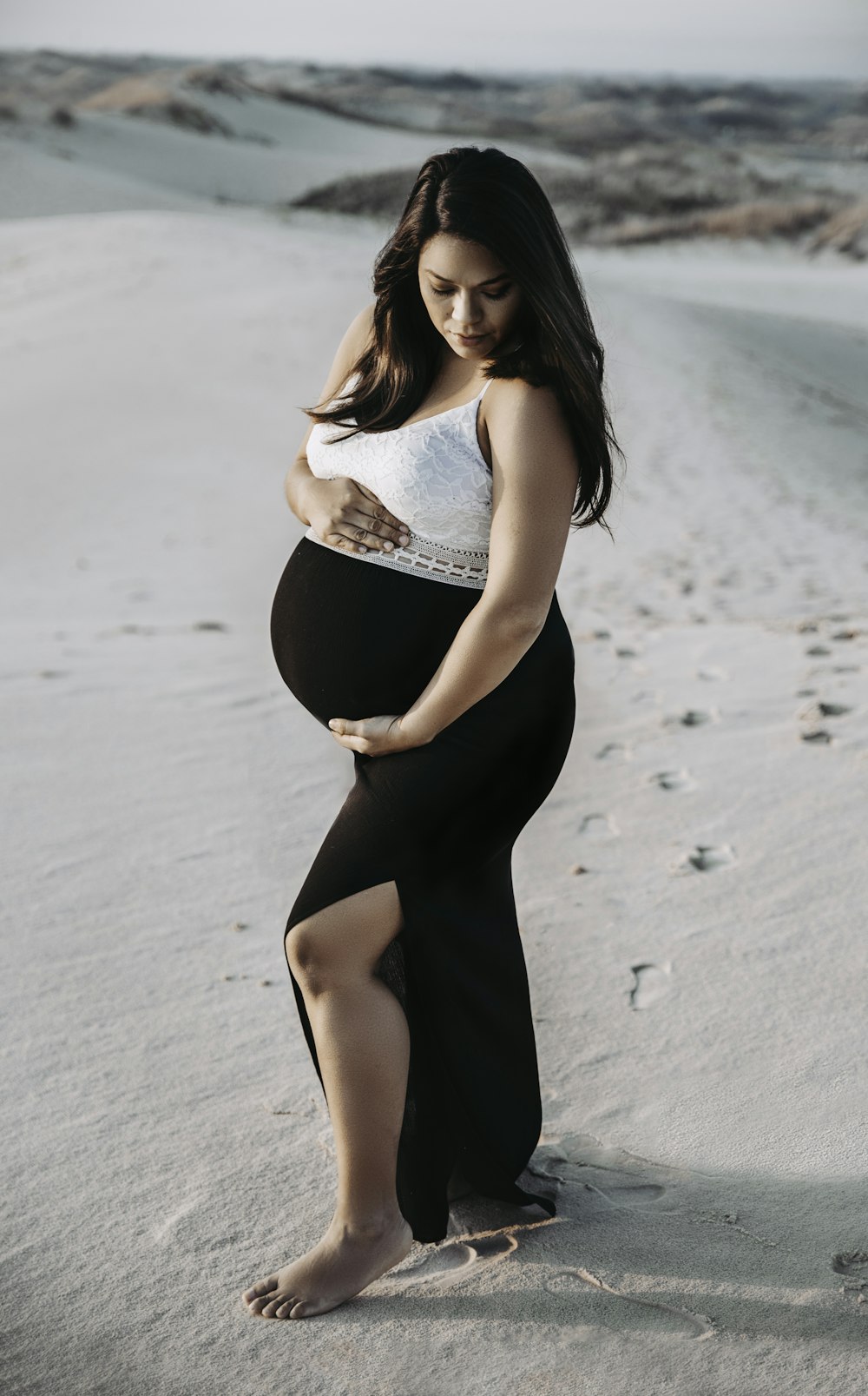 a pregnant woman standing in the sand