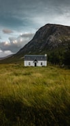 white and gray concrete house on plant field beside mountain