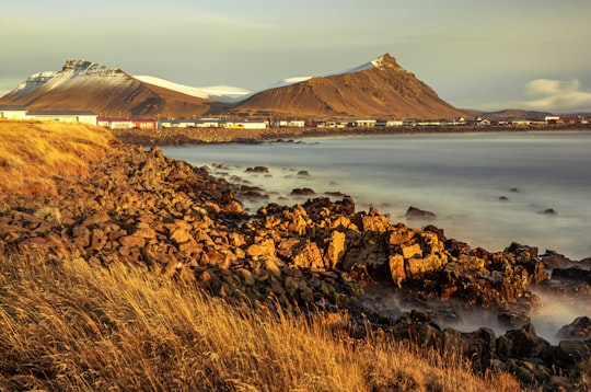 rocky island with buildings during day in Akranes Iceland