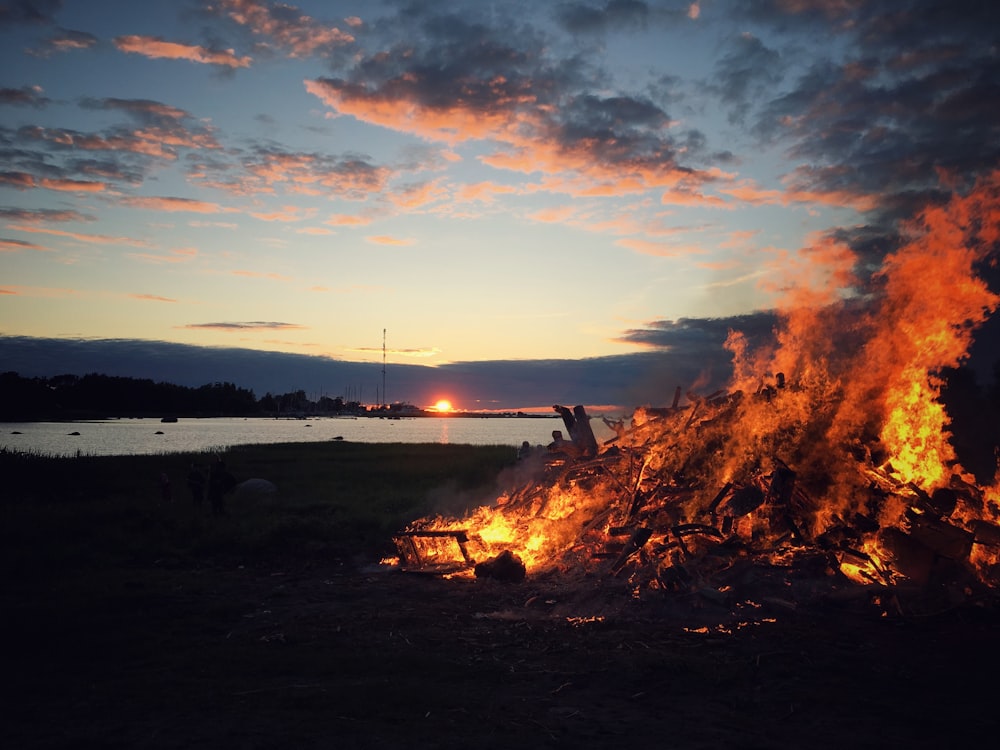 Sehen Sie sich die Fotografie eines Feuers in der Nähe des Sees während der Morgendämmerung an