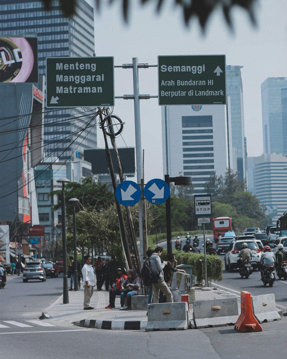 view photography of people sitting and standing in the middle of road island during daytime