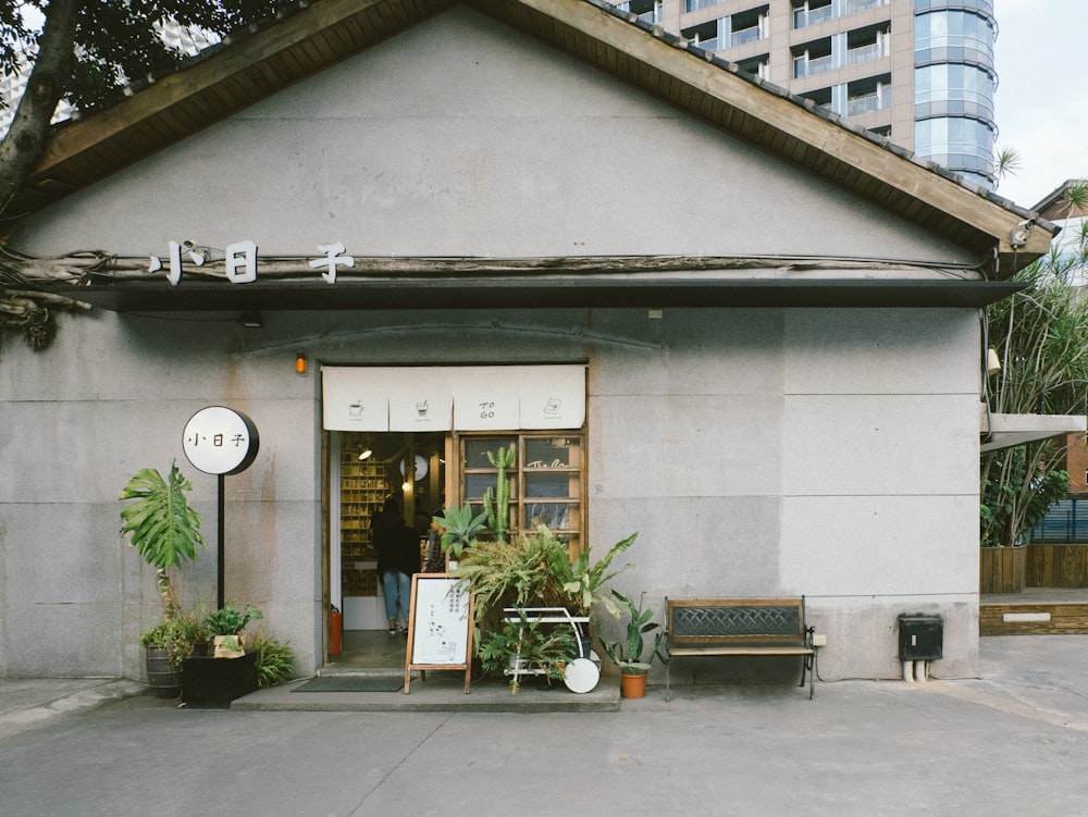 brown wooden outdoor bench near green leaf plants beside white building