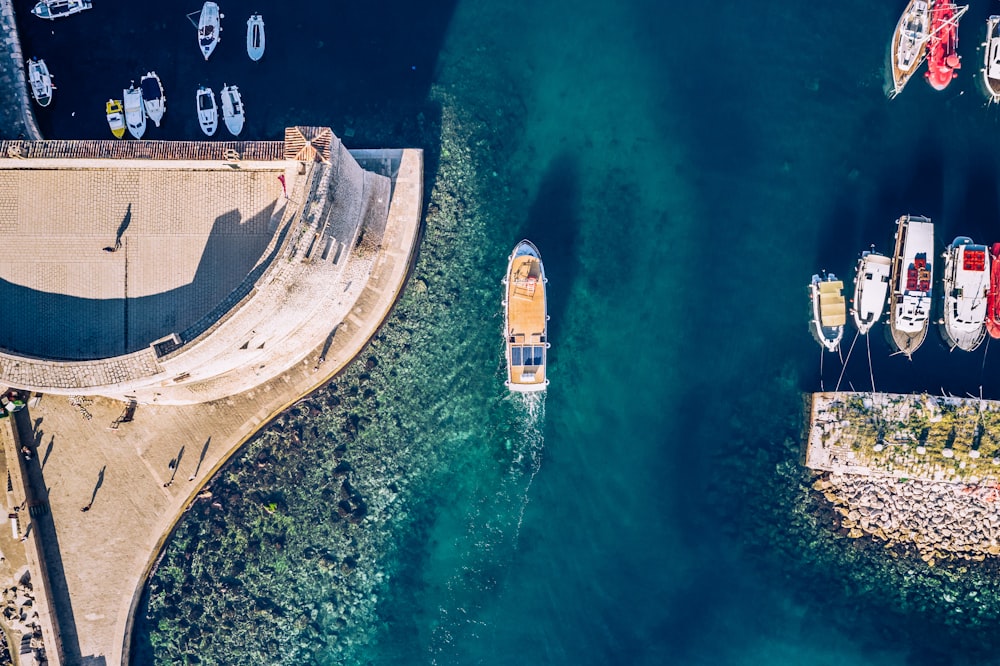 aerial photography of assorted-colored yachts on blue sea near brown historic building during daytime