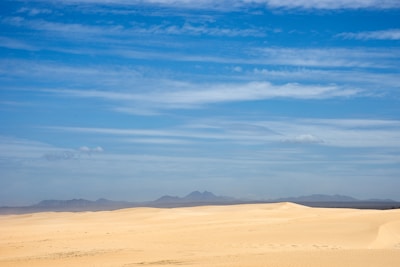 A panoramic view of golden Sahara dunes stretching endlessly beneath a clear blue sky.