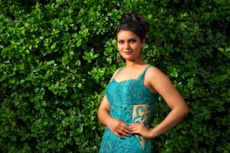 A woman with styled hair and makeup, ready for a formal event, against a scenic outdoor backdrop.