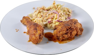 A steaming plate of golden fried chicken accompanied by fresh coleslaw and crispy fries on a rustic wooden table.