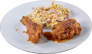 A vibrant plate featuring hot chicken sliders with pickles and coleslaw.