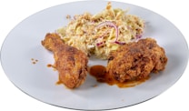 A plate featuring two pieces of crispy fried chicken accompanied by a serving of creamy coleslaw garnished with red onion slices.