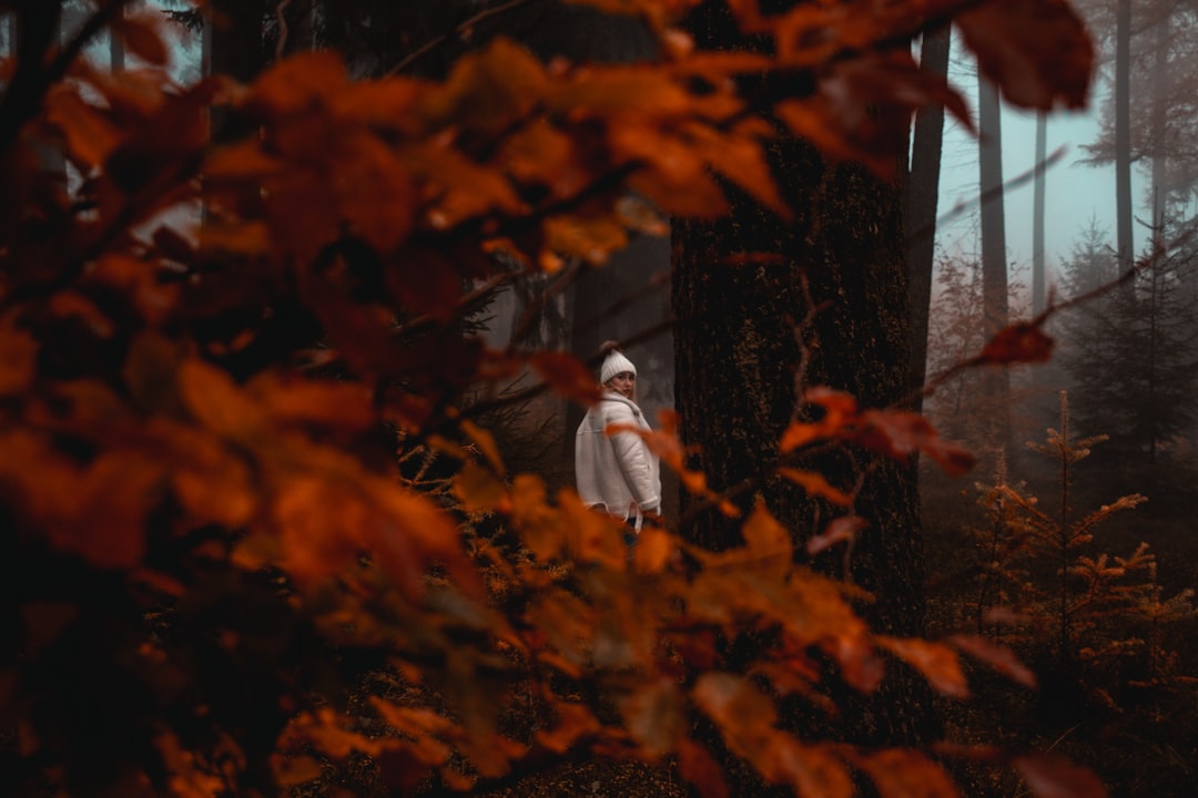 woman wearing white jacket standing near tree in foggy day