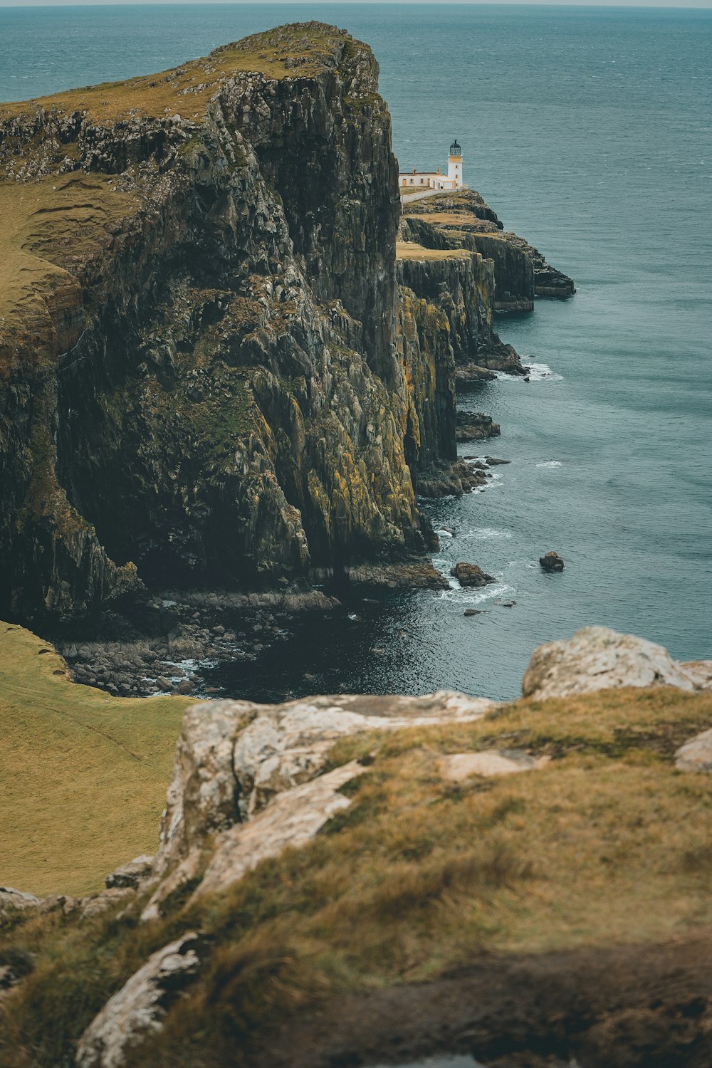 white lighthouse on cliff viewing body of water during daytime