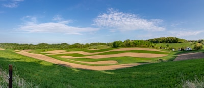 A panoramic view of a family farm with rolling hills and fenced pastures.