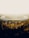 Aerial view of a large, circular building surrounded by trees. The structure has a sleek, modern design with a reflective surface and appears to be part of a sprawling corporate campus. Sunlight filters through the haze, creating a warm, golden hue over the scene.