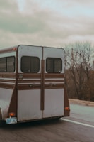 A horse trailer being carefully loaded for transport on a country road.