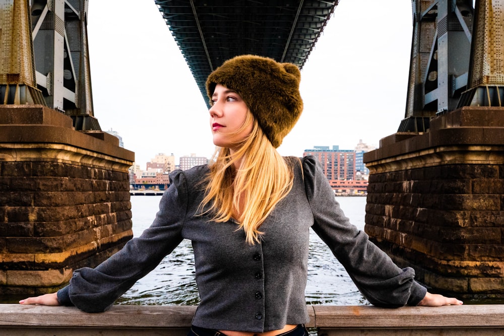 woman in gray jacket standing under bridge
