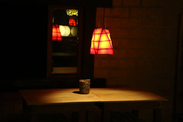 A warm-lit wooden table with a stylish modern lamp casting a soft glow.