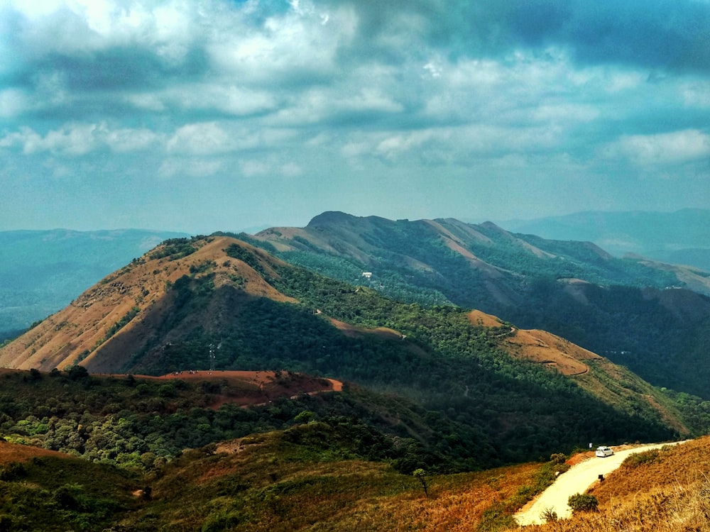 aerial photography of green field viewing mountain under blue and white sky