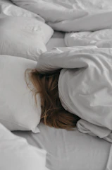 Side view of a person resting peacefully on the Derila pillow in a softly lit bedroom