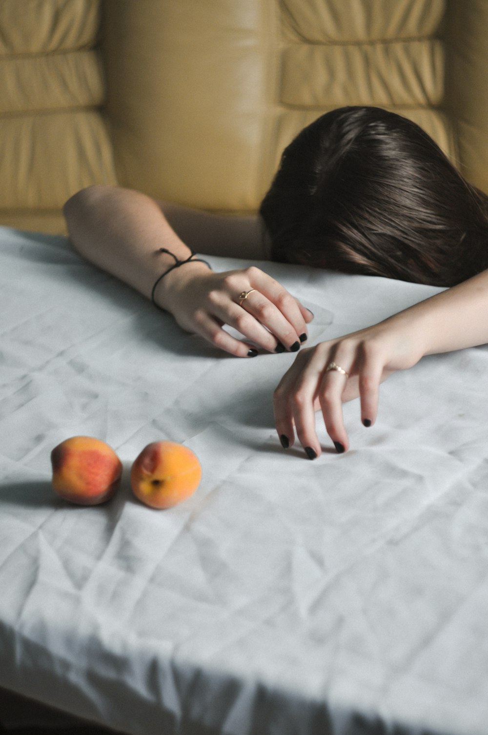 woman leaning on white textile near fruits