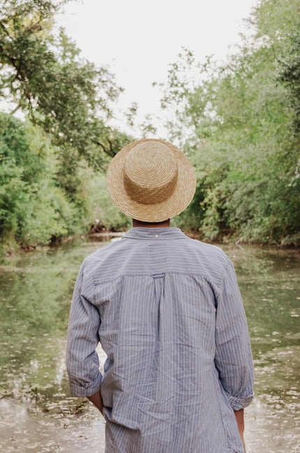 person in gray dress shirt standing near lake during daytime