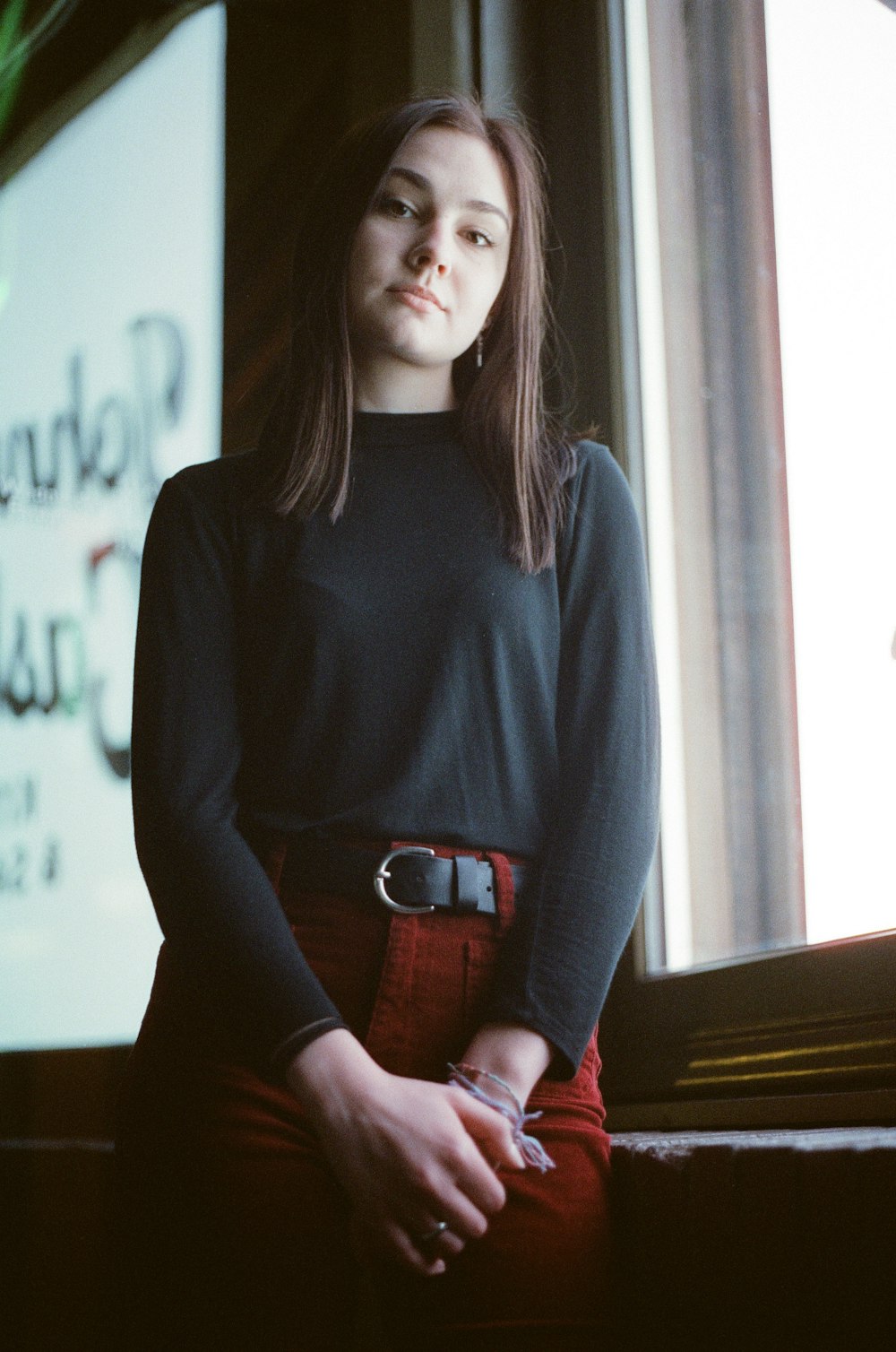 woman standing near window wearing black long-sleeved shirt during daytime