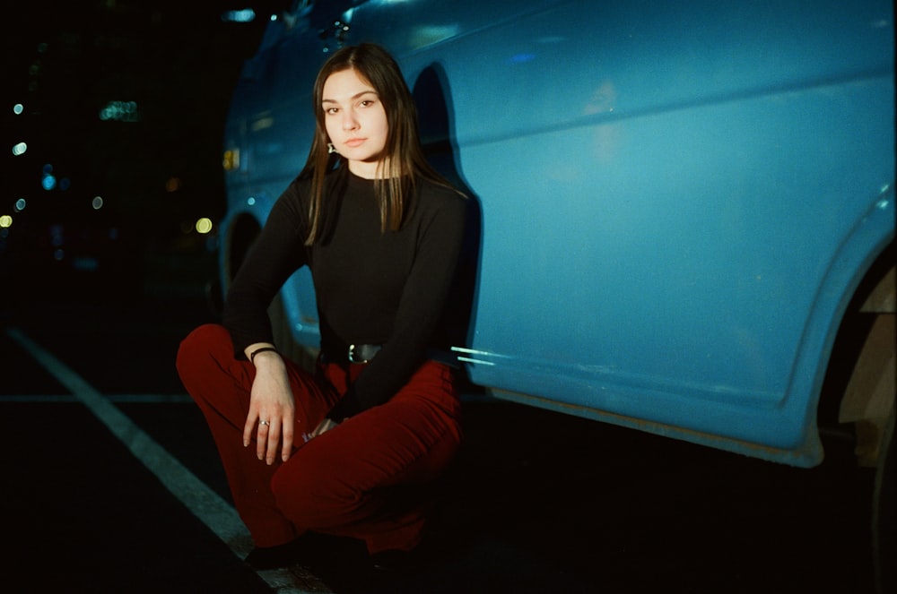 woman sitting beside car