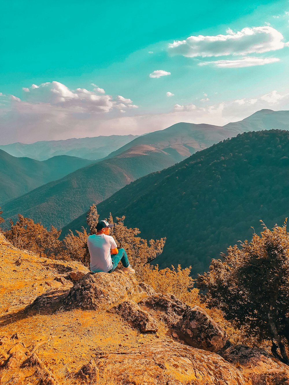 man sitting on stone hill during daytime