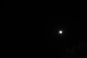 The image captures a solar eclipse against a dark sky, with a bright halo of light emerging from behind the moon, creating a striking contrast.