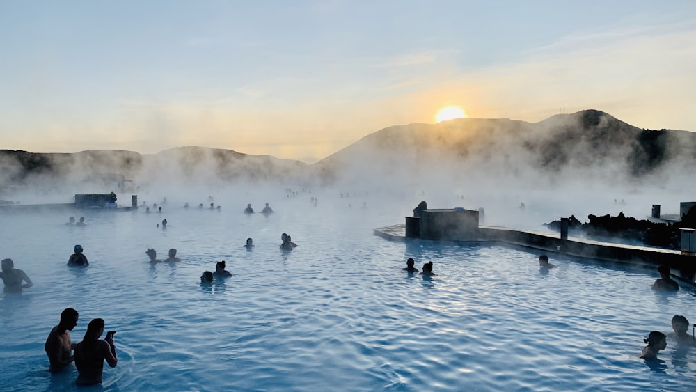 people on body of water near mountain during golden hour