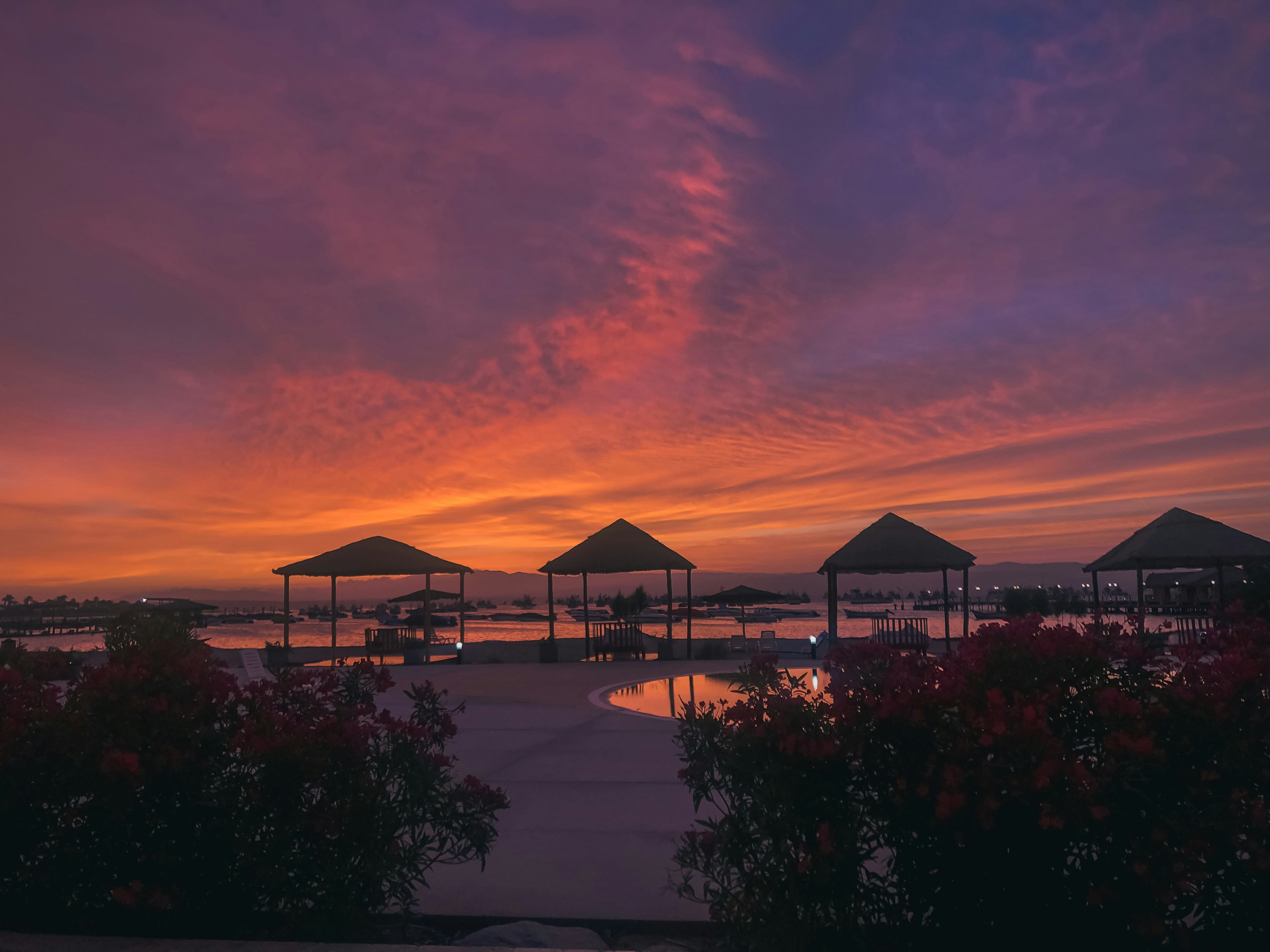 Lakeside resort with thatched chalets reflected in still water at sunset