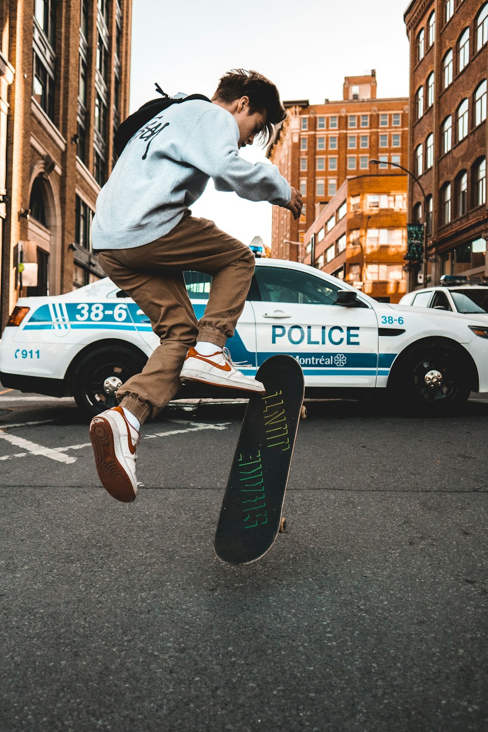 man doing exhibition on skateboard in front of police vehicle during daytime