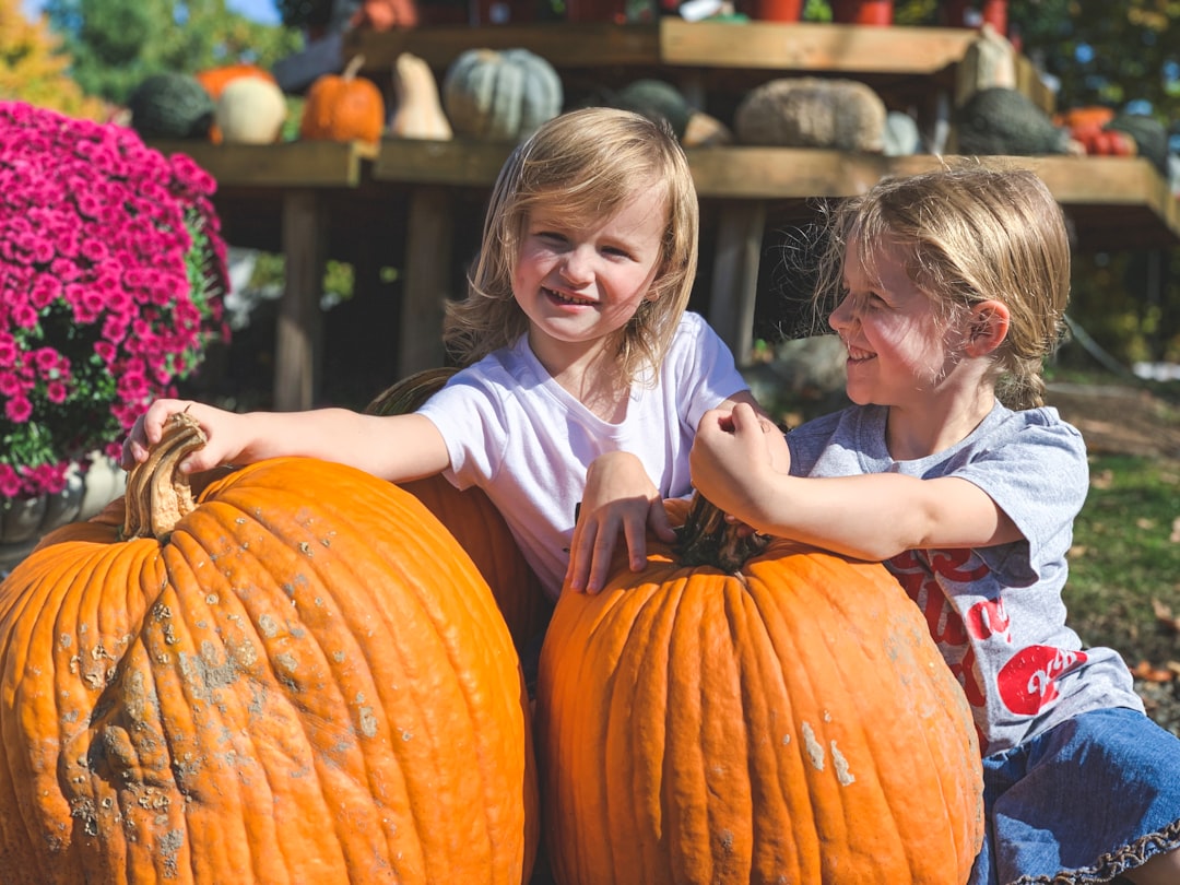 two smiling girls holding pumpkins